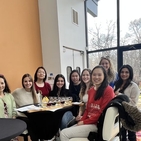 A group of women in radiology sit at a table smiling at the camera